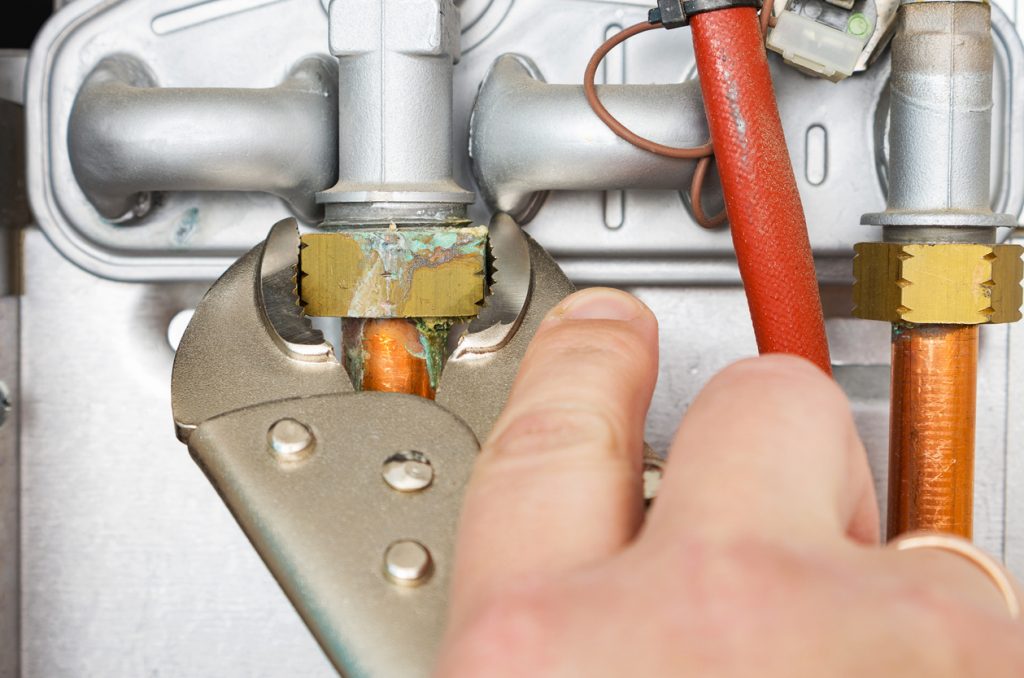 Plumber repairing a leaking gas boiler of a heating home system