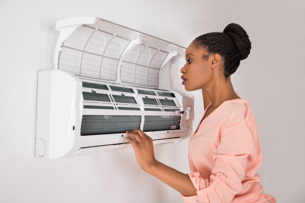 Young African Woman Checking Air Conditioner At Home