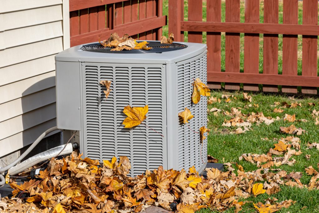 Dirty air conditioning unit covered in leaves during autumn. Home air conditioning, HVAC, repair, service, fall cleaning and maintenance